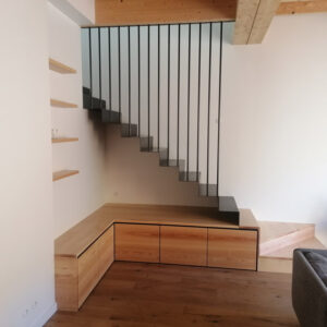 Escalier sur mesure suspendu en métal fin, posé dessus un meuble en bois